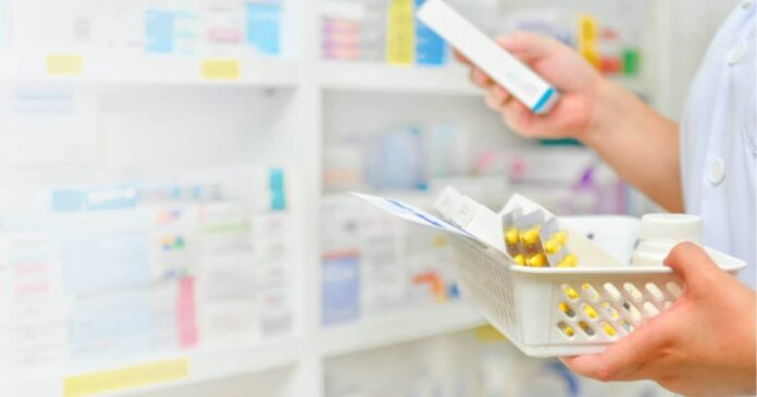 Image of a pharmacist reading the label of a medication box.