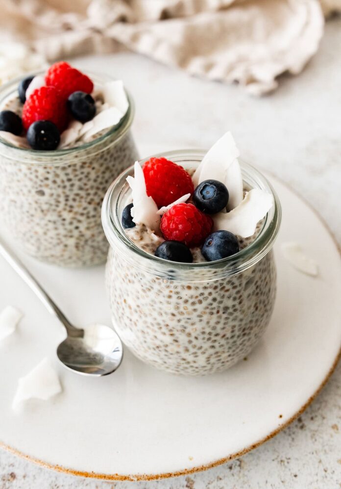 Coconut chia pudding in a glass cup, topped with fresh berries.