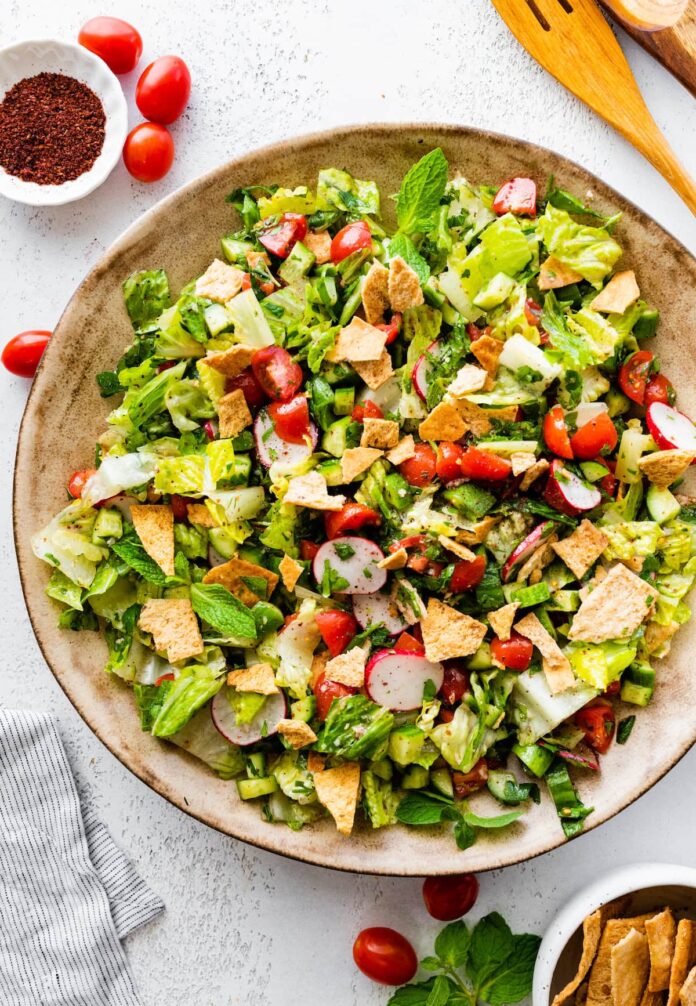 A large bowl of fattoush salad with ingredients like radishes, cherry tomatoes, lettuce, pita chips, and more.