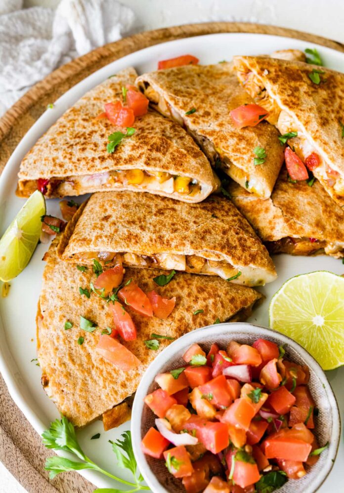 Healthy chicken quesadilla on a plate with a side bowl of pico de gallo.