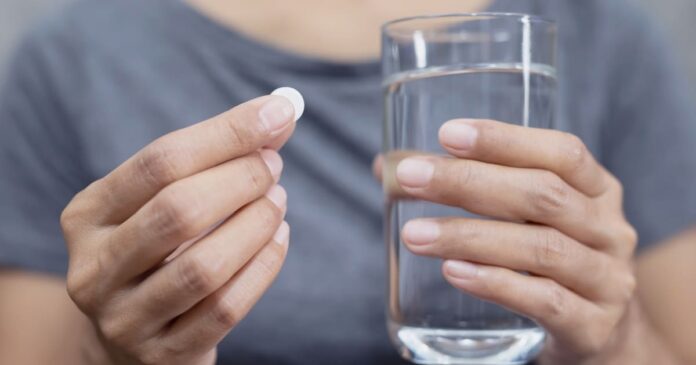 Person holding metformin pill and glass of water