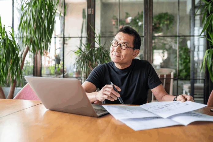 mature asian man with laptop thinking