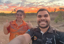 Milestone achievements strengthen First Nations diabetes leadership Josiah Little and Louise Gilbey give a thumbs up with a desert/scrub background at sunset.
